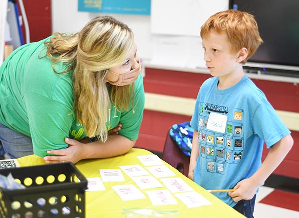 Student teacher leaning in, listening to young student